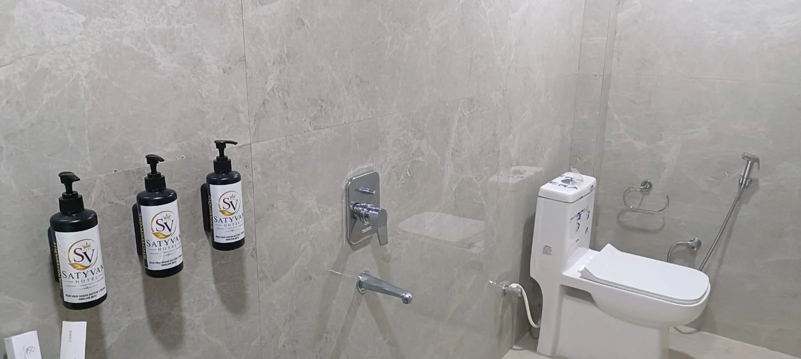 Modern tiled bathroom vanity at Satyvan Hotel equipped with clean fixtures, a basin, and complimentary guest toiletries
