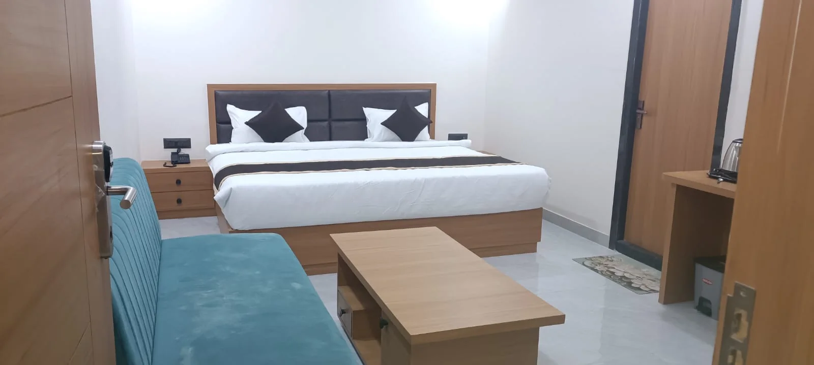 Polished residential-style hotel room at Satyvan Hotel near Vinay Nagar with a comfortable upholstered headboard and warm ambient lighting