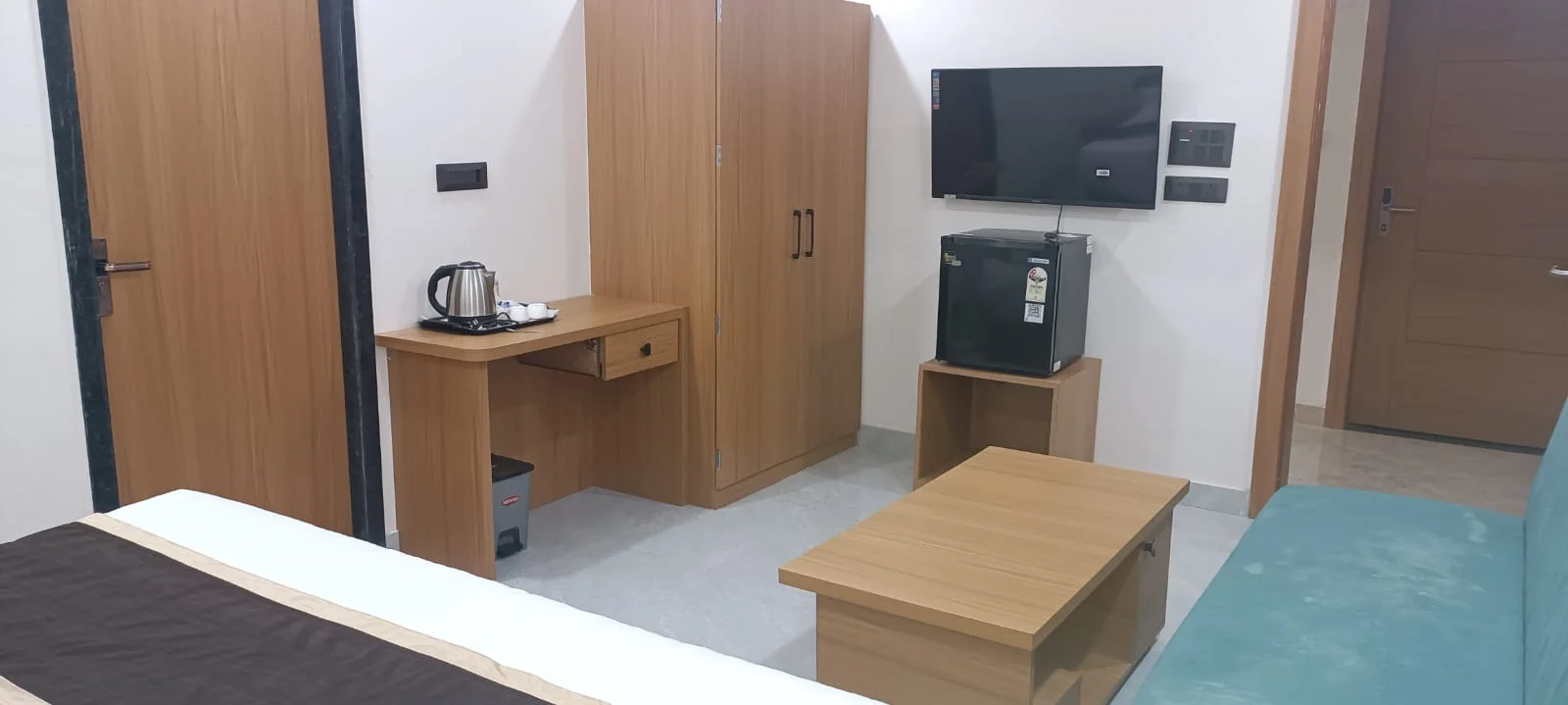 Satyvan Hotel Gwalior air-conditioned 4-star guest room featuring a king bed with a teal runner and a dedicated work desk
