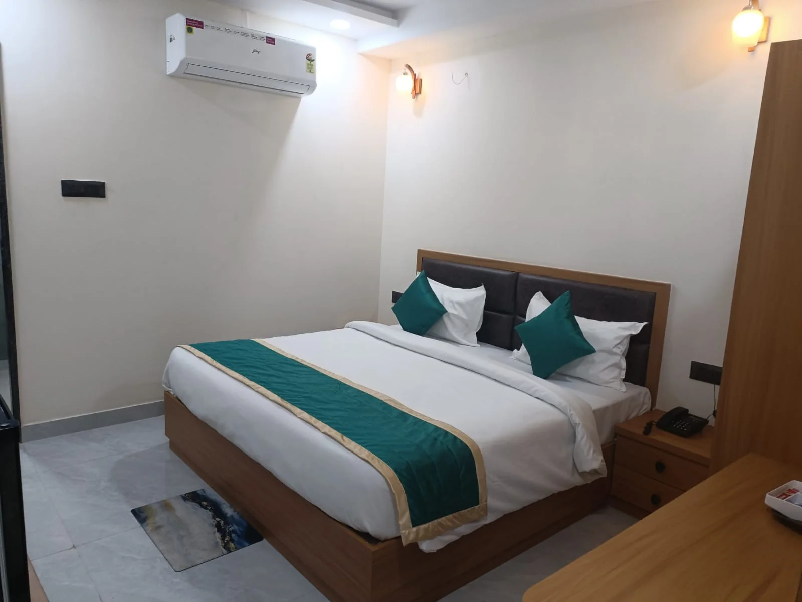 Spacious guest room layout at Satyvan Hotel Gwalior with flat-screen TV, seating area, mini fridge, and wood furnishings